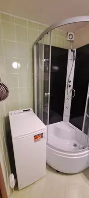 a small shower in a bathroom with a white refrigerator at Apartamentai The 56 Spot in Utena