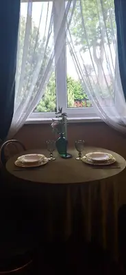 a table with two plates and glasses and a window at Boho House in Šiauliai