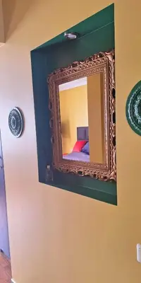 a mirror on a wall with a bed in a room at Boho House in Šiauliai