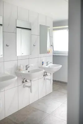 a white bathroom with two sinks and a mirror at Degučiai ,svečių namai in Šakiai