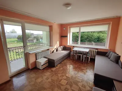 a living room with a couch and a table and windows at Degučiai ,svečių namai in Šakiai