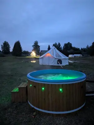 a large hot tub in a field with a tent at Anos Kempingas, Troškūnai in Smėlynė
