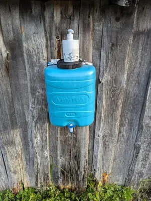 a blue water hydrant attached to a wooden fence at Anos Kempingas, Troškūnai in Smėlynė