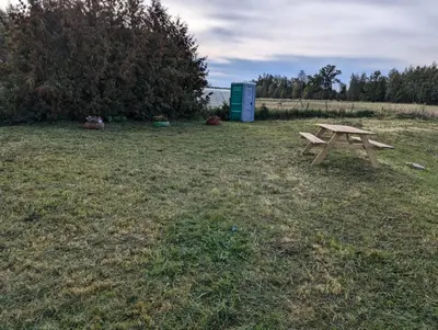 a picnic table sitting in the middle of a field at Anos Kempingas, Troškūnai in Smėlynė