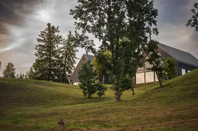 a house on top of a hill with a tree at Aukštoji Liškiava in Liškiava