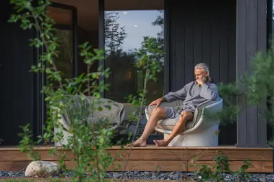 a man sitting on a toilet outside of a house at Aukštoji Liškiava in Liškiava