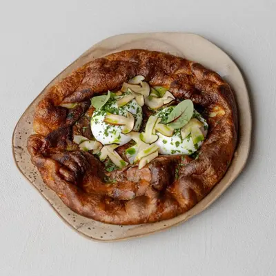 a pizza sitting on a plate on a table at Aukštoji Liškiava in Liškiava