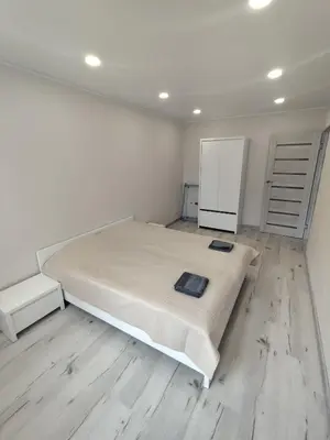 a white bedroom with a bed and a refrigerator at J&N Hause in Visaginas