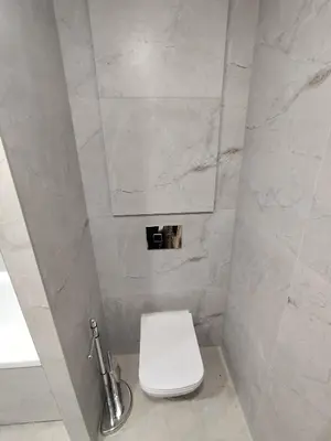a bathroom with a white toilet and marble walls at J&N Hause in Visaginas