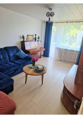 a living room with a blue couch and a table at Pušų lašas apartamentai in Birštonas