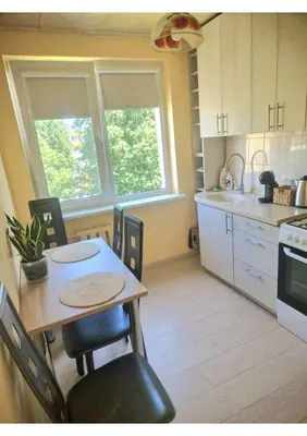 a kitchen with a table and chairs in a room at Pušų lašas apartamentai in Birštonas