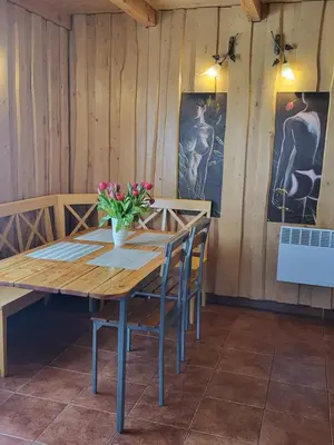 a wooden table with chairs and a vase of flowers on it at Namelis Rugilė in Druskininkai