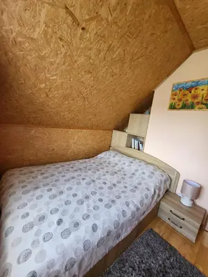 a small bedroom with a bed and a painting on the wall at Namelis Rugilė in Druskininkai