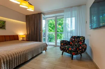 a bedroom with a bed and a chair and a window at Park apartment in Druskininkai