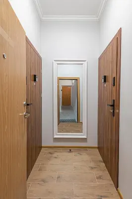 a hallway with two wooden doors and a mirror at The Comfort Apartment #2 by Polo Apartments in Kaunas