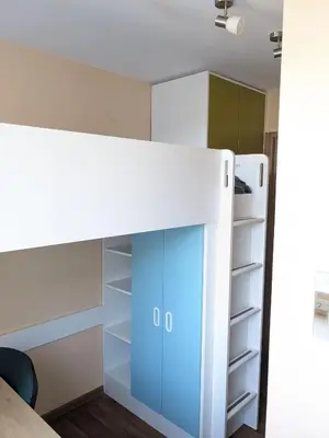 a bedroom with a bunk bed with blue cabinets at Tiny Studio Apartment in Kaunas