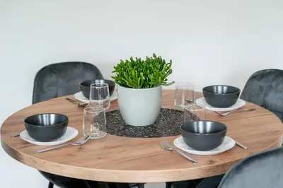 a wooden table with plates and bowls and a potted plant at Central Location I Private Garage Parking & Easy Checkin I Cᴏʜᴏsᴛ in Vilnius
