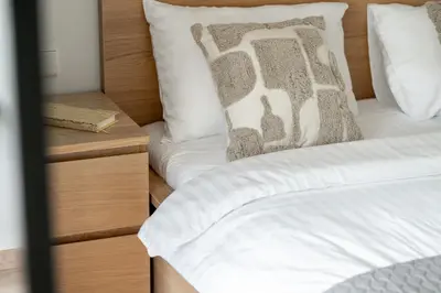 a bedroom with two beds and a wooden nightstand at Central Location I Private Garage Parking & Easy Checkin I Cᴏʜᴏsᴛ in Vilnius