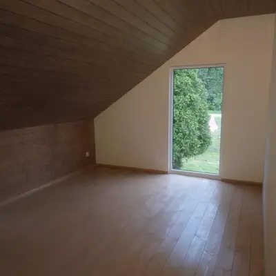 an empty room with a large window and wooden floors at Draugų sodyba