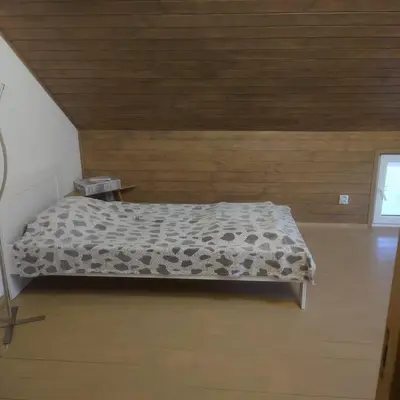 a bed in a room with a wooden wall at Draugų sodyba