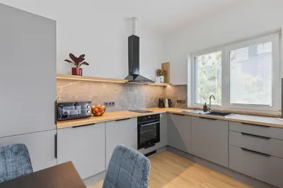 a kitchen with white cabinets and a table with chairs at Niwaki Sodai No 3 by URBAN RENT in Vilnius