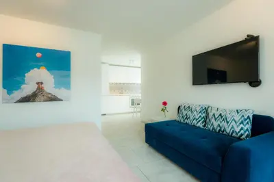 a living room with a blue couch and a flat screen tv at Ice apartment in Druskininkai