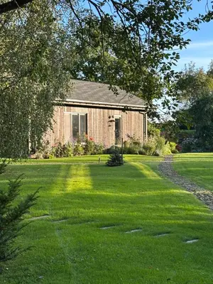 an old barn with a grass yard in front of it at Pramogų namelis