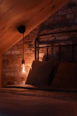 a bedroom with a bed with a lamp and a brick wall at Pramogų namelis