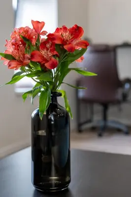 a black vase filled with red flowers on a table at Vincent Urban Nest - Near Clinic, Arena and Stadium in Kaunas