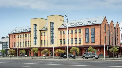 a building with cars parked in front of a street at Vincent Urban Nest - Near Clinic, Arena and Stadium in Kaunas