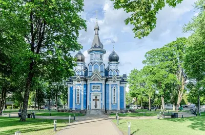 a blue building in a park with trees at Nemunas A respite Studio 8 in Druskininkai
