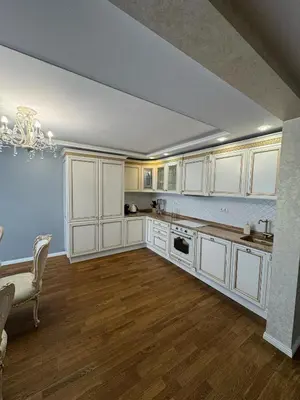 a kitchen with white cabinets and a table and a dining room at Classic Style Apartment in Kelmė
