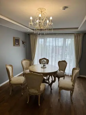 a dining room with a table and chairs and a chandelier at Classic Style Apartment in Kelmė
