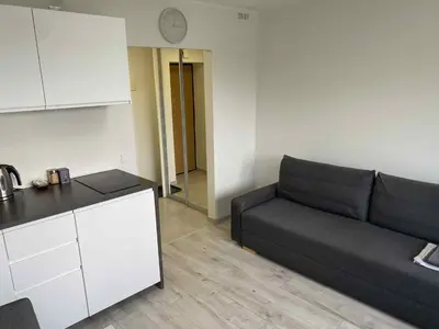 a living room with a couch and a clock on the wall at Vilnius Apartment with Balcony in Vilnius