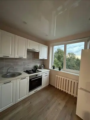a kitchen with white cabinets and a sink and two windows at MB BENO TRUMPALAIKE NUOMA LUKSIUKAs in Kėdainiai