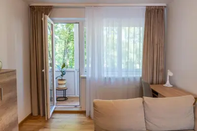 a living room with a couch and a large window at Saulės laikrodžio apartamentai in Šiauliai