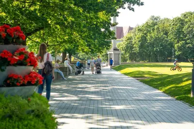people walking down a sidewalk in a park at Saulės laikrodžio apartamentai in Šiauliai