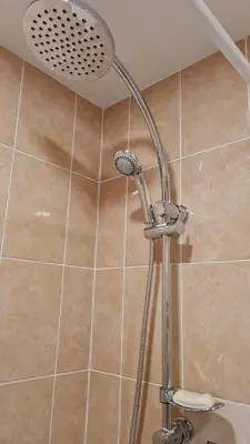 a shower with a shower head in a bathroom at Saulės laikrodžio apartamentai in Šiauliai