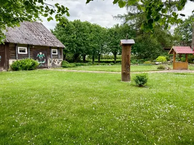 a birdhouse in a yard next to a house at Prienų vienkiemis in Kelmė