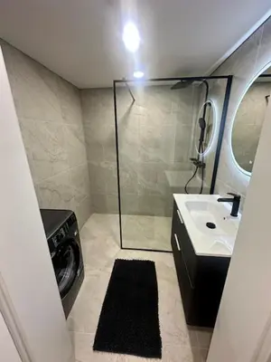a bathroom with a shower and a sink and a washing machine at Butas nuomai truputį daugiau nei kilometras pėsčiomis iki Senamiesčio in Kaunas