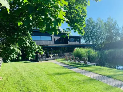 a house with a row of chairs in the grass at Villa Emilė in Kontverki
