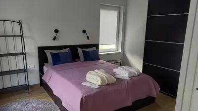 a bedroom with a purple bed with towels on it at Lake apartments in Rokiškis