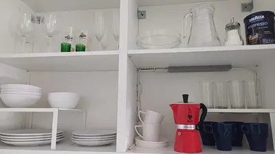 a kitchen cabinet filled with dishes and wine glasses at Lake apartments in Rokiškis