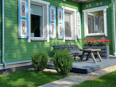 a green house with a wooden bench and a table at Lake apartments in Rokiškis