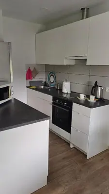 a kitchen with white cabinets and a black counter top at Lake apartments in Rokiškis