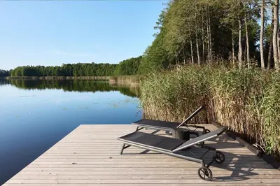 a picnic table sitting on a dock next to a lake at Juoda Truoba