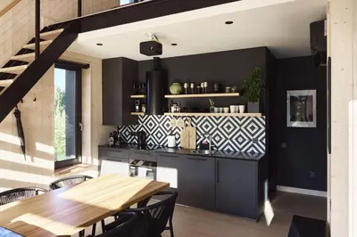 a kitchen with black cabinets and a wooden table at Juoda Truoba