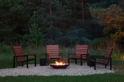three chairs sitting around a fire pit in a yard at Juoda Truoba