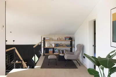 a room with a staircase with two chairs and a book shelf at Juoda Truoba