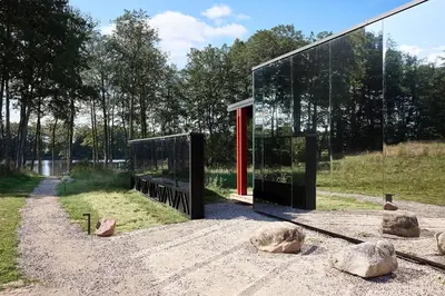 a glass house with a red door in a field at Juoda Truoba